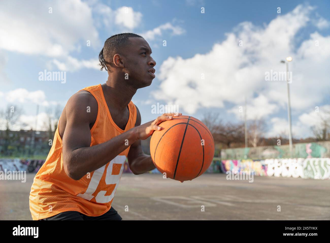 Uomo che gioca a basket sul campo all'aperto Foto Stock