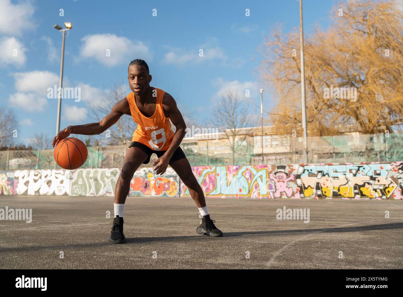 Uomo che rimbalza la palla da basket sul campo all'aperto Foto Stock