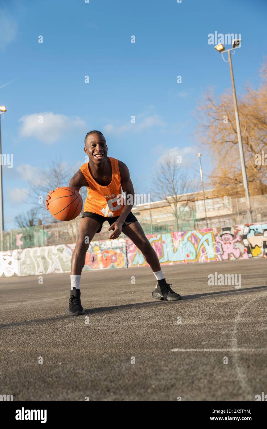 Uomo che rimbalza la palla da basket sul campo all'aperto Foto Stock