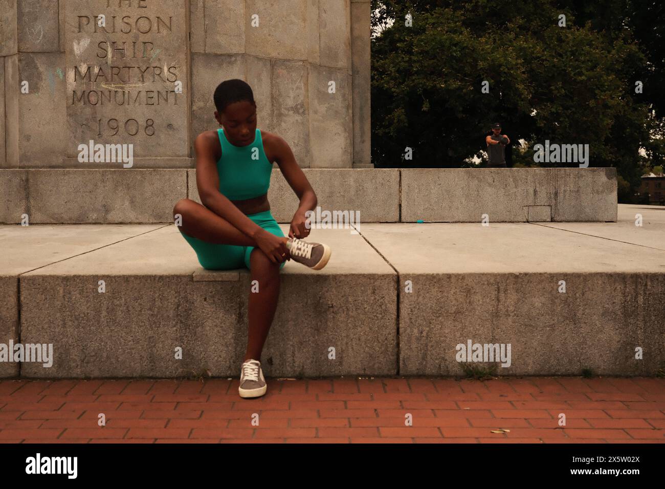 USA, New York, donna in abbigliamento sportivo seduta al monumento Foto Stock