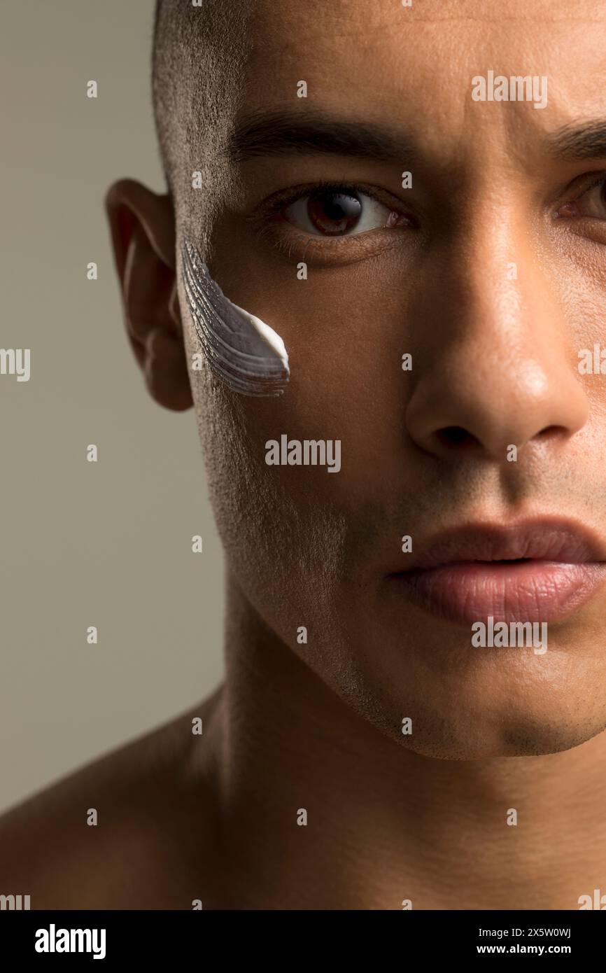 Primo piano di un uomo con crema per il viso sulla guancia Foto Stock