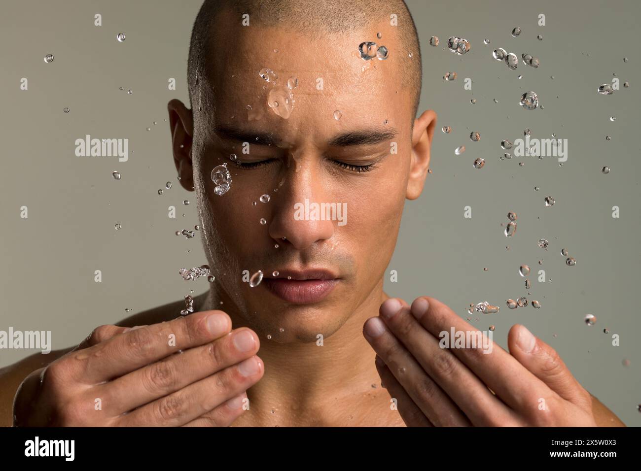 Ritratto in studio dell'uomo che spruzza acqua sul viso Foto Stock