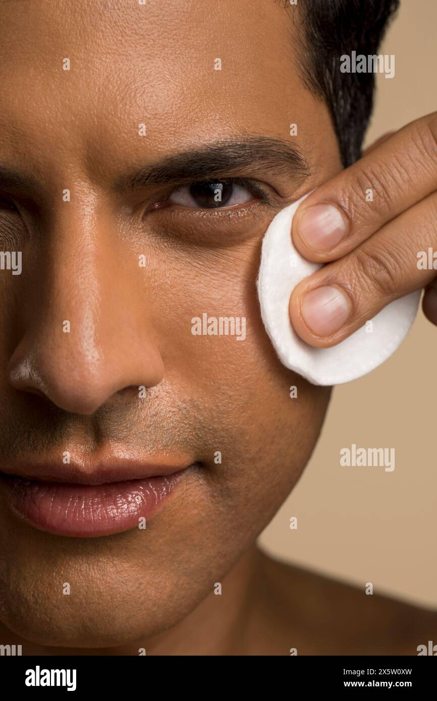Primo piano di un uomo che pulisce il viso con un panno di cotone Foto Stock