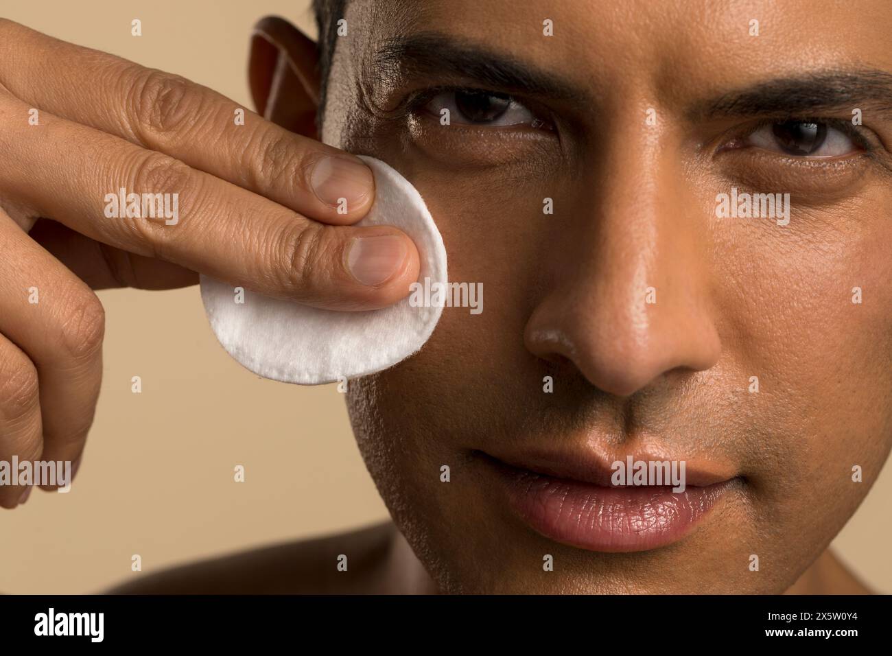 Primo piano di un uomo che pulisce il viso con un panno di cotone Foto Stock