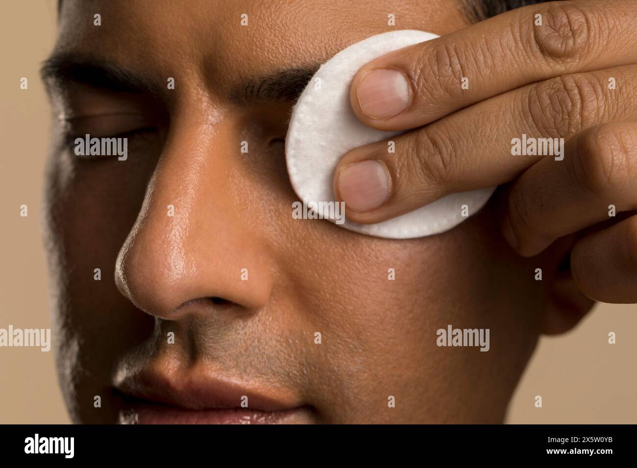 Primo piano di un uomo che pulisce il viso con un panno di cotone Foto Stock