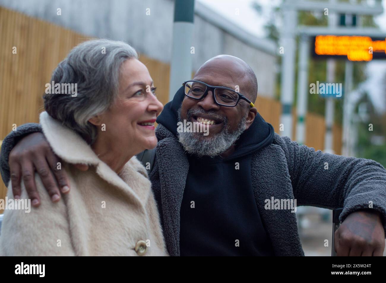 Coppia senior in attesa al binario della stazione ferroviaria Foto Stock