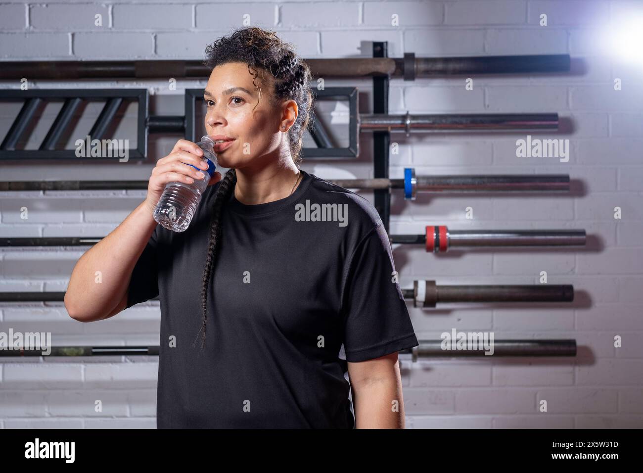 Donna acqua potabile dalla bottiglia in palestra Foto Stock