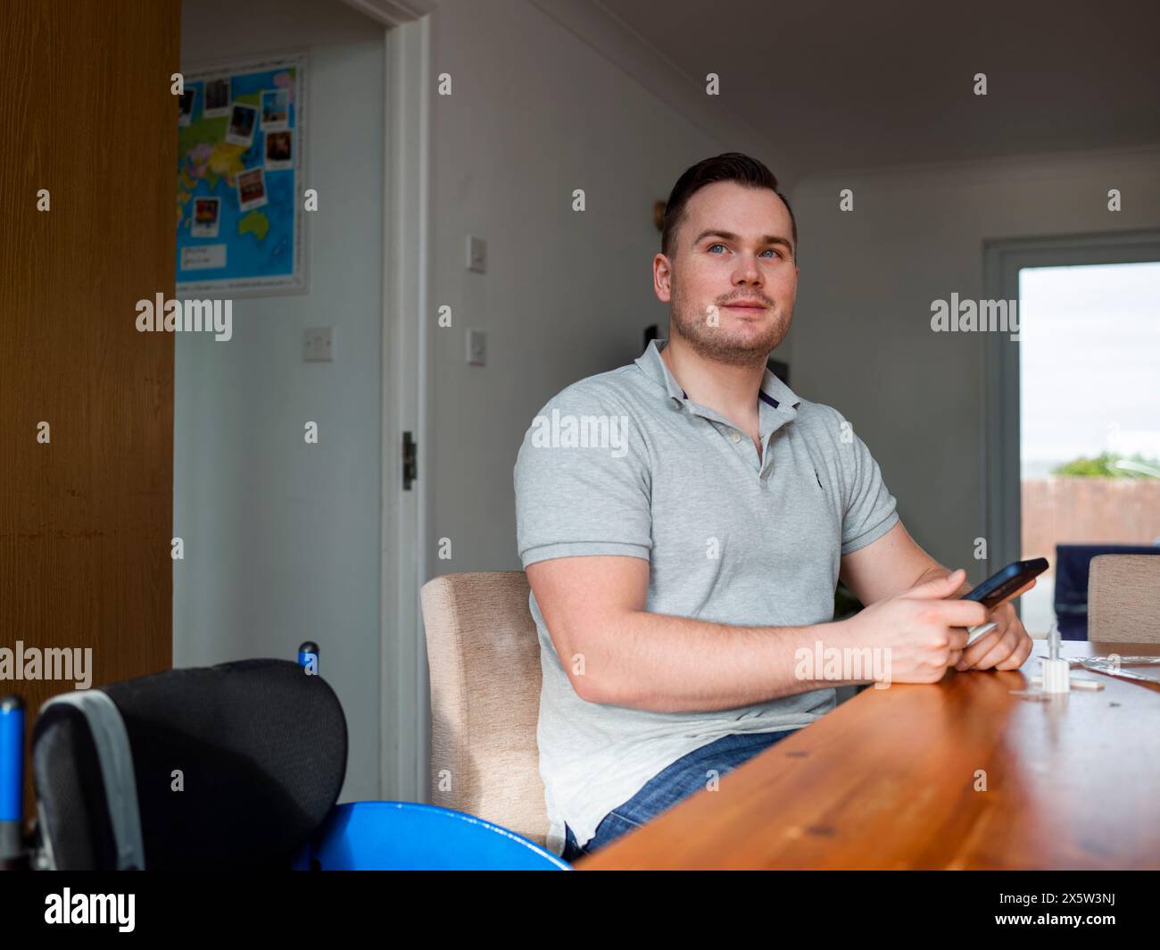 Uomo seduto a tavola con smartphone e test del coronavirus domestico Foto Stock