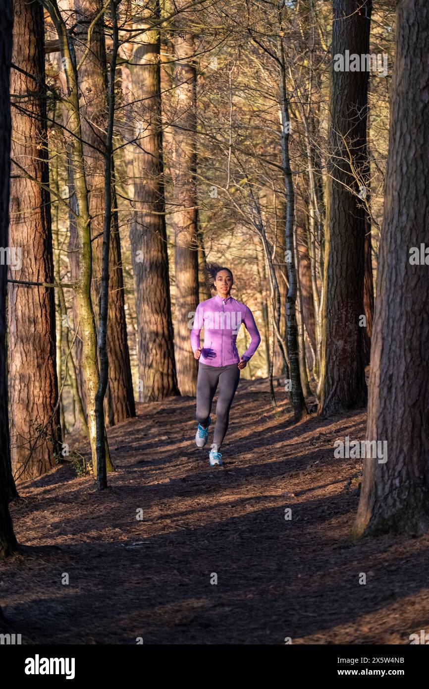 Giovane donna jogging in foresta Foto Stock