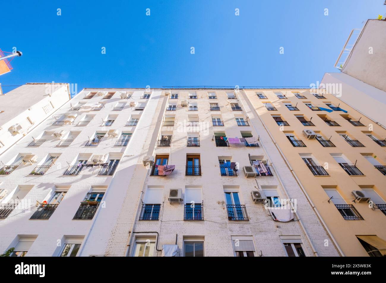 Vista frontale di un enorme e alto edificio multifamiliare in cui si possono vedere stili di vita diversi e vestiti appesi che si asciugano nell'aria Foto Stock