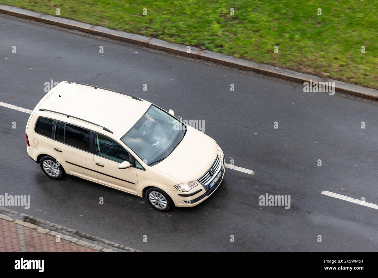 OSTRAVA, REPUBBLICA CECA - 23 MARZO 2024: Vettura monovolume beige Volkswagen Touran con effetto di sfocatura del movimento in caso di pioggia Foto Stock