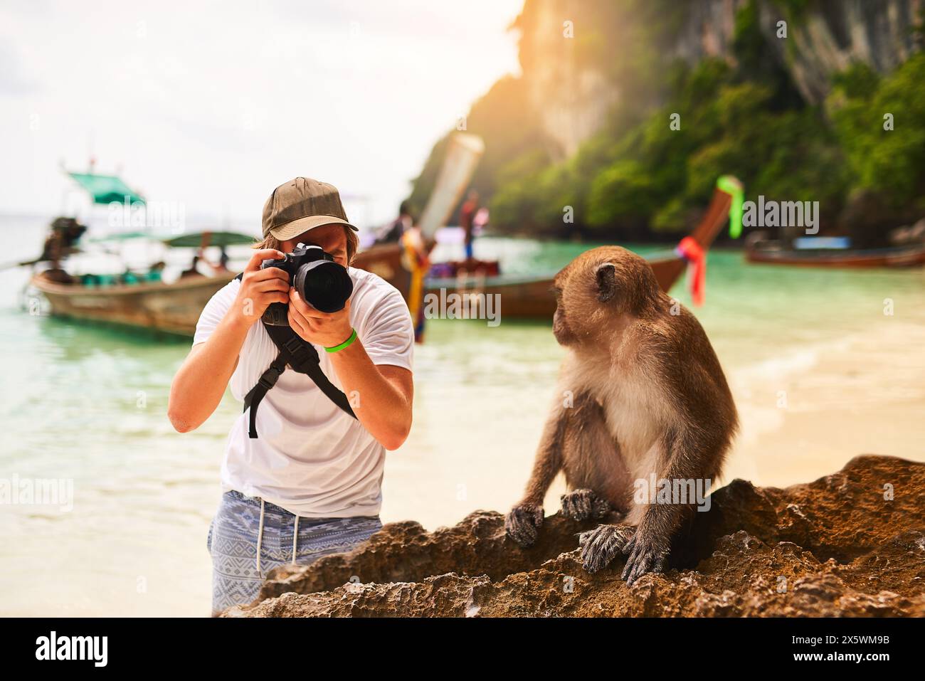 Uomo, macchina fotografica e scimmia con vacanza, spiaggia e isola tropicale con viaggio breve, Bali e viaggio. Persona, fotografo e turista al sole Foto Stock
