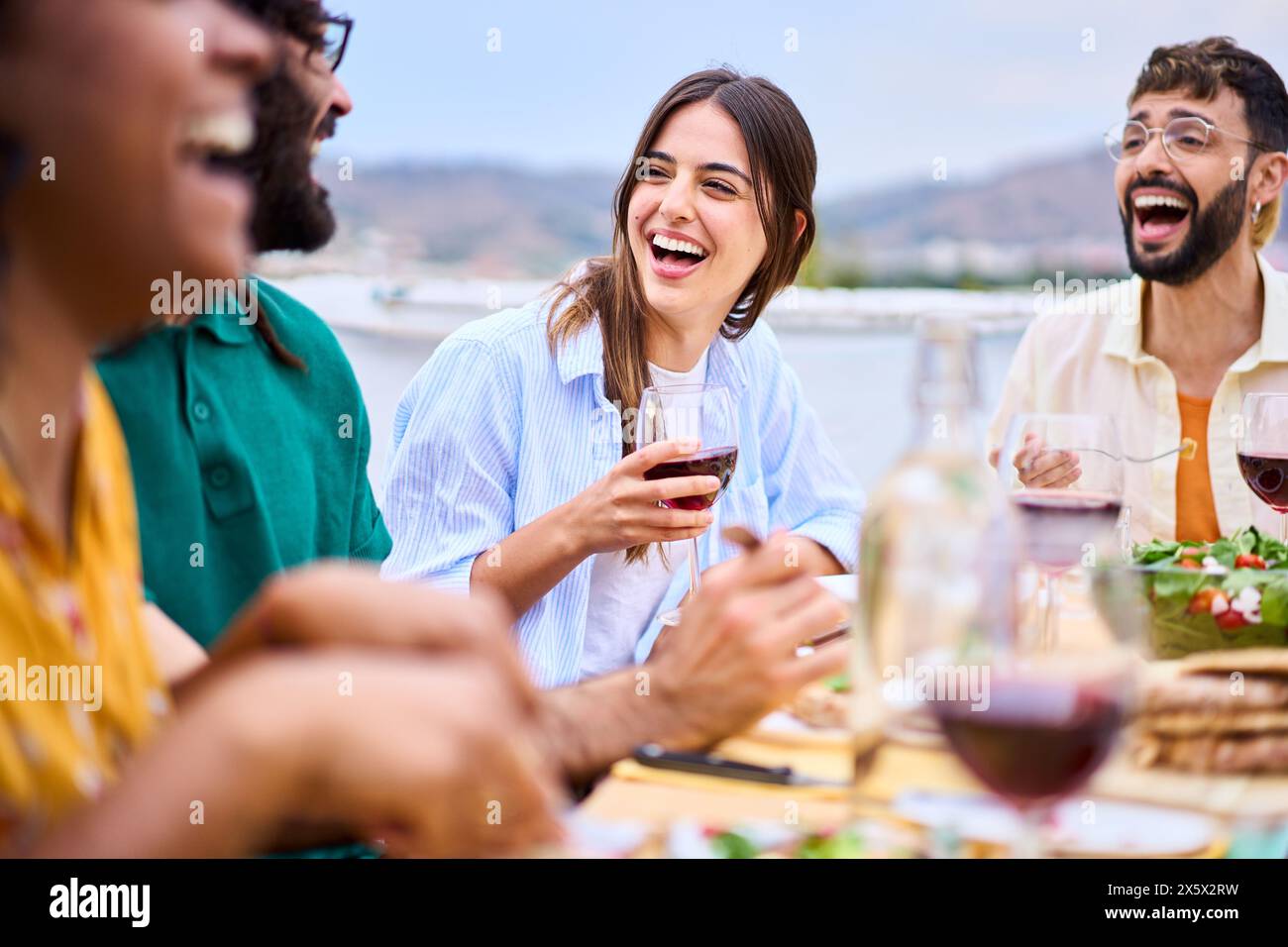 Un gruppo di giovani amici millenari che ridono si è riunito per una festa estiva al barbecue all'aperto. Foto Stock