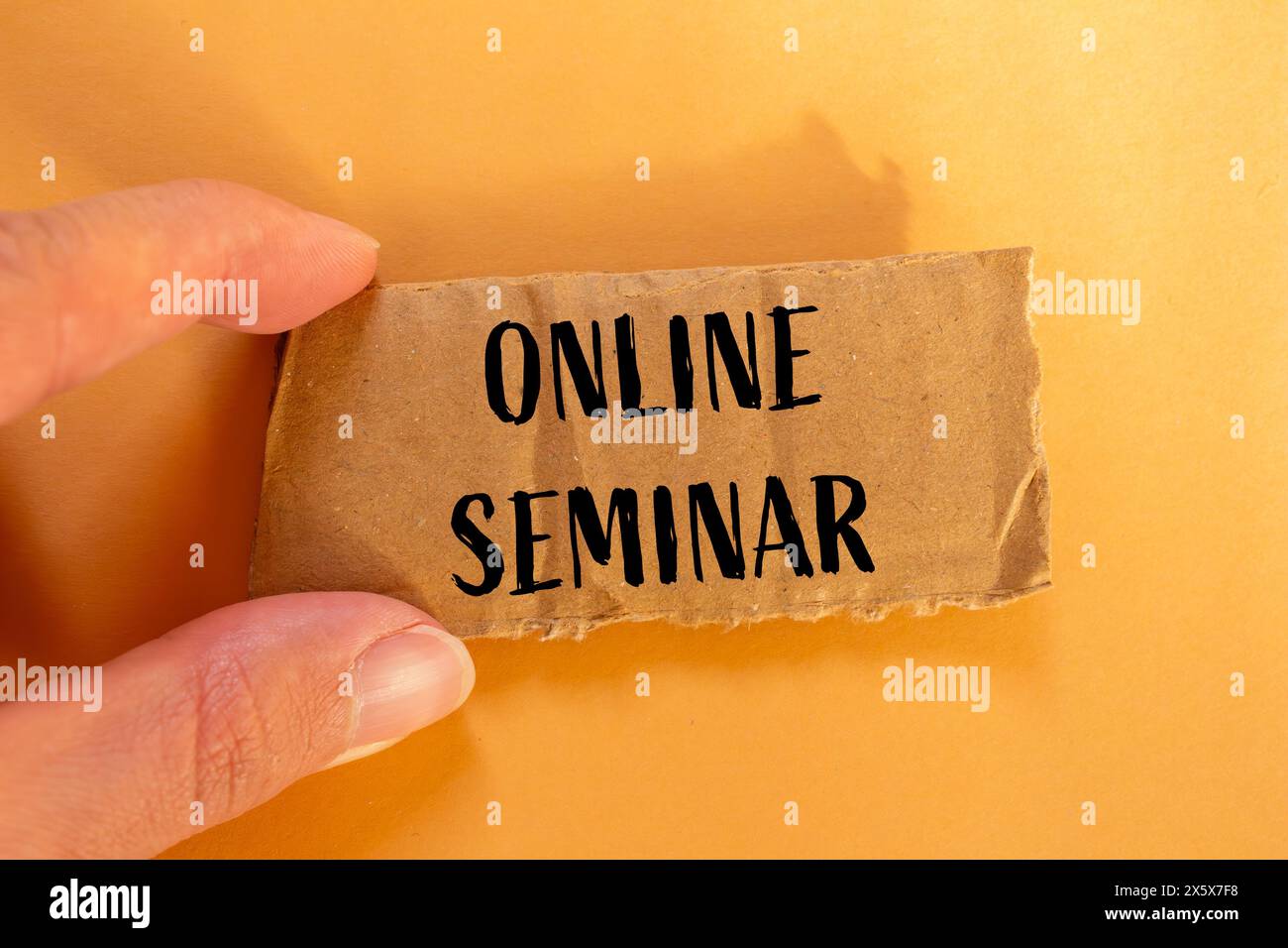 Seminario online scritto su un pezzo di carta di cartone strappato con sfondo arancione. Simbolo del seminario online concettuale. Copia spazio. Foto Stock