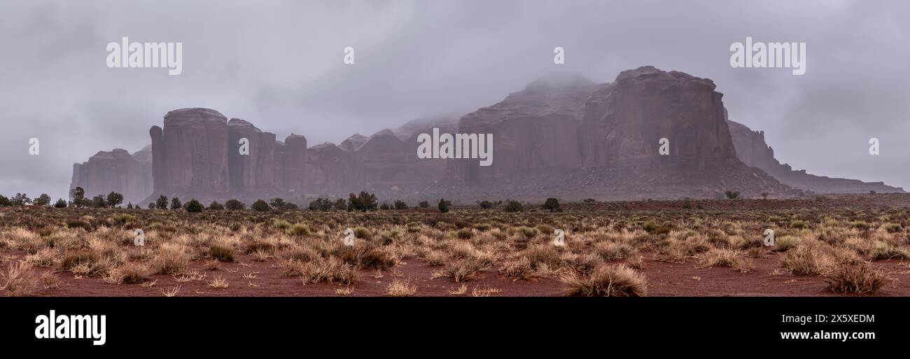 Molte aree all'interno della Monument Valley ospitano formazioni montuose più piccole. Qui è mostrata una formazione durante una giornata di pioggia con basse nuvole che rivestono struc rocciosi Foto Stock
