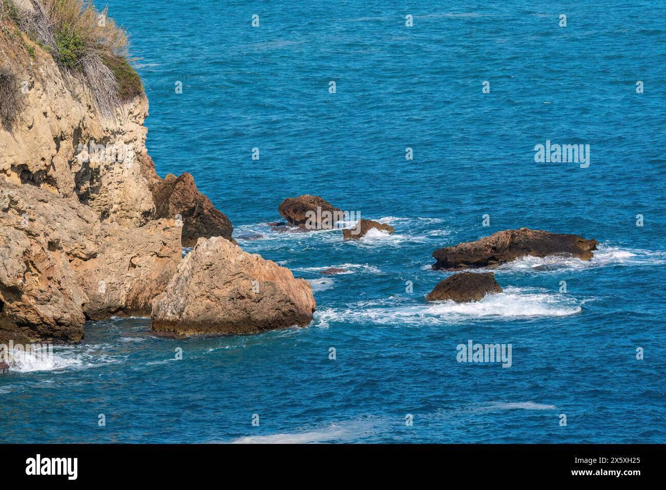 Onde di un mare blu profondo che si infrangono contro le rocce di Antalya in Turchia Foto Stock