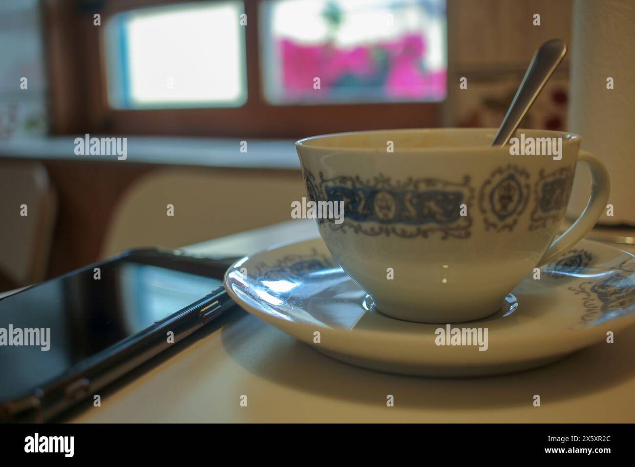 una tazza di caffè e un telefono cellulare la mattina presto Foto Stock