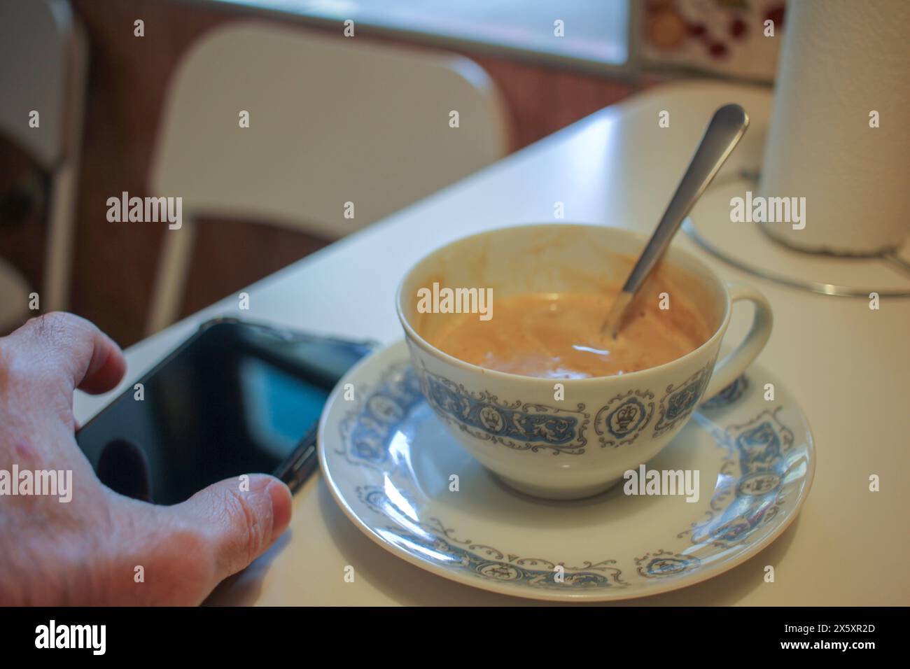 prima cosa, la mattina, prendere una tazza di caffè e guardare un telefono cellulare Foto Stock