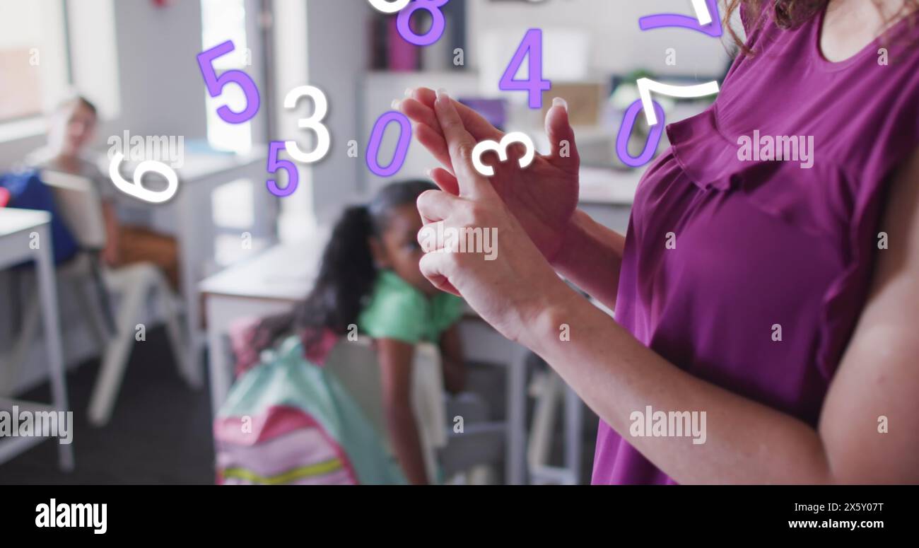 Immagine di numeri che si spostano su un'insegnante birazziale felice che spiega a diverse classi scolastiche Foto Stock