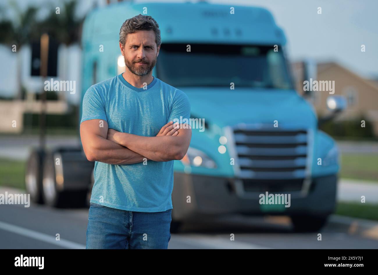 Conducente uomo vicino camion camion. Conducente di camion proprietario uomo in t-shirt vicino camion. Bell'uomo di mezza età che camionista proprietario. Industria dei trasporti Foto Stock