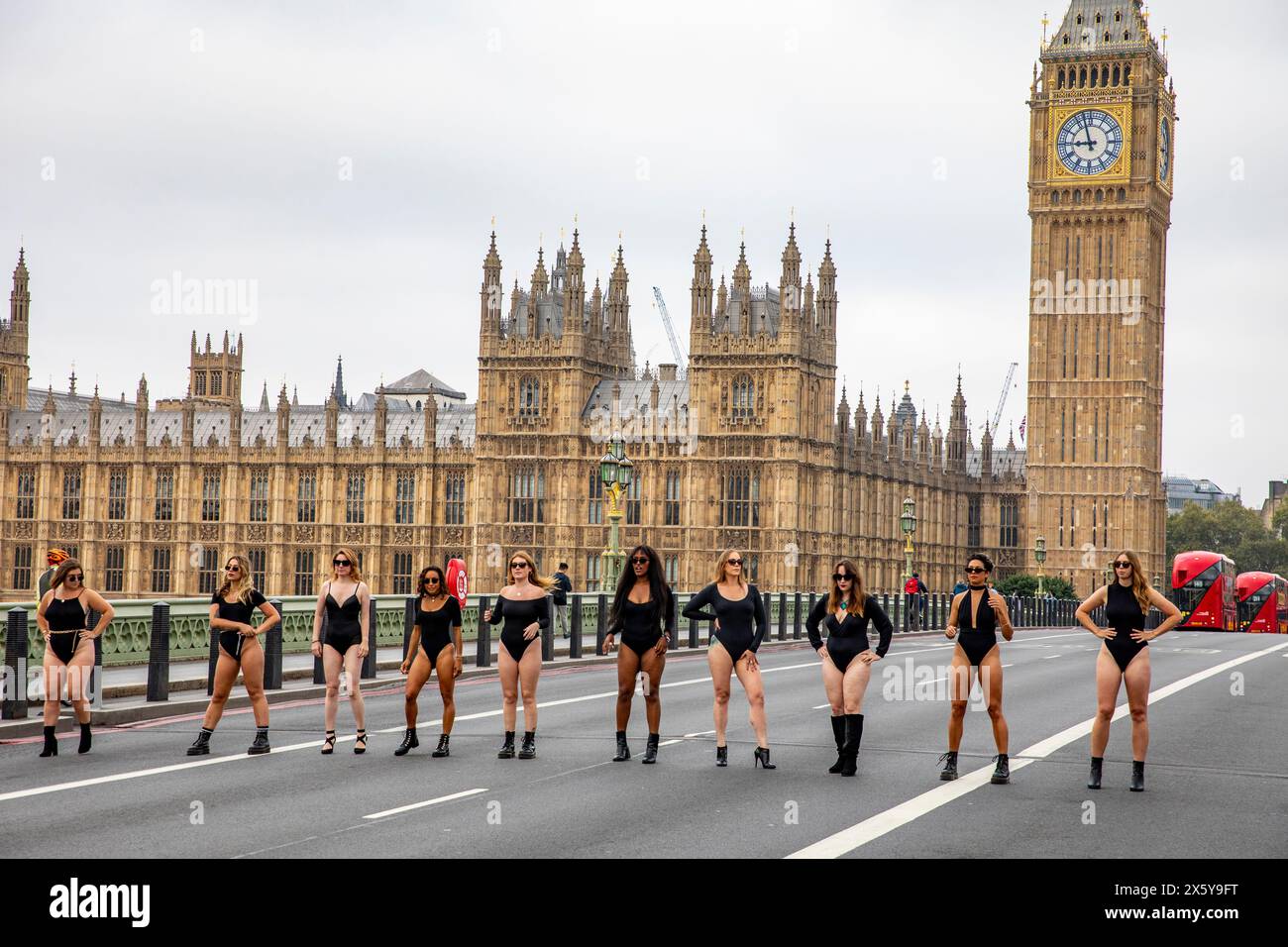 Le donne in grembiule nere camminano lungo il ponte di Westminster a Londra con il Palazzo del Parlamento alle spalle, Londra, Inghilterra, Regno Unito, 2023 Foto Stock