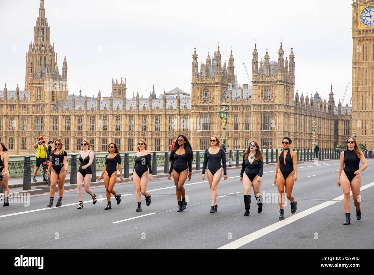 Le donne in grembiule nere camminano lungo il ponte di Westminster a Londra con il Palazzo del Parlamento alle spalle, Londra, Inghilterra, Regno Unito, 2023 Foto Stock