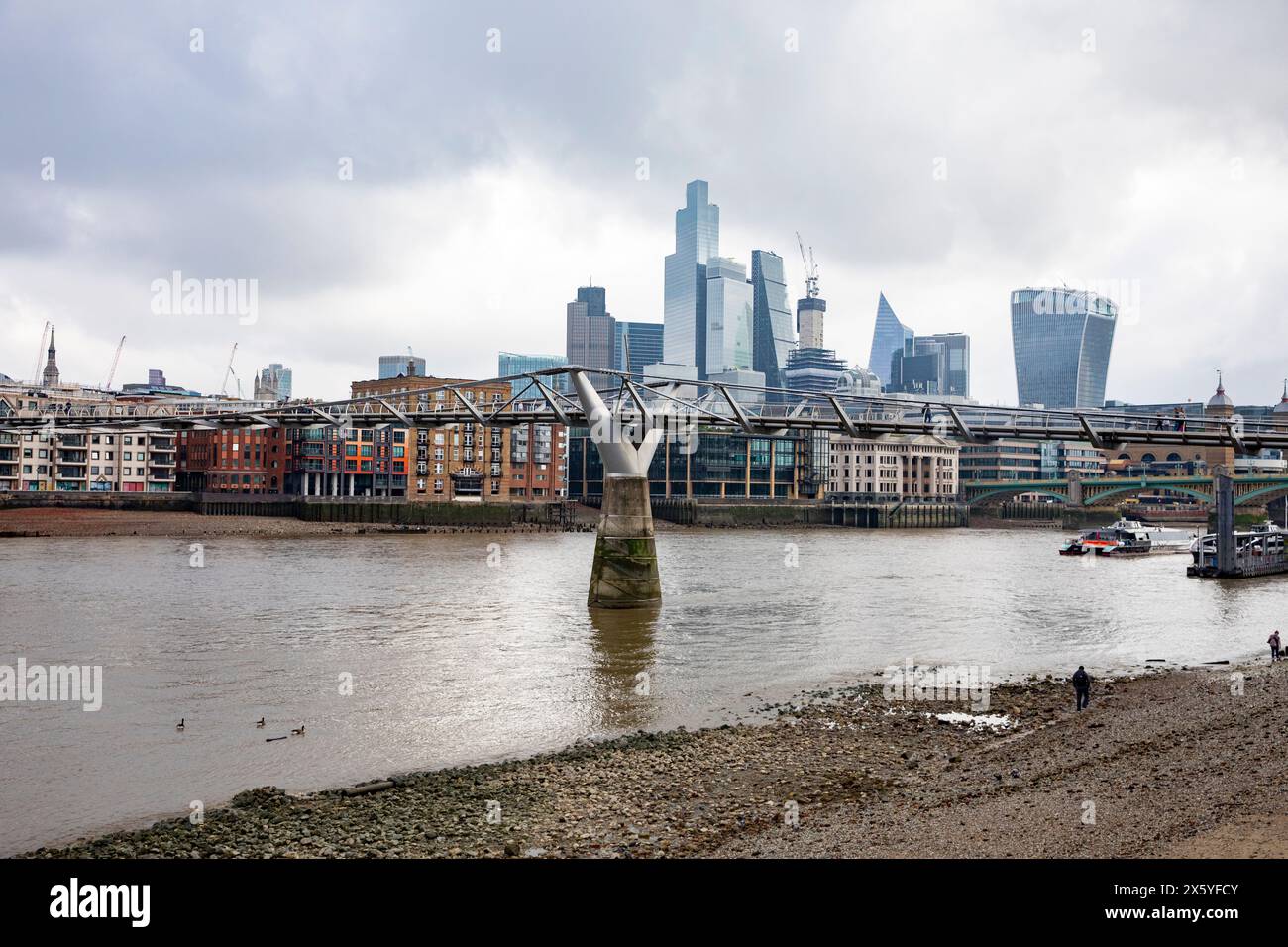 Il Tamigi con la bassa marea con persone che camminano lungo la riva del Tamigi, lo skyline della città di Londra in lontananza, Londra, Inghilterra, 2023 Foto Stock