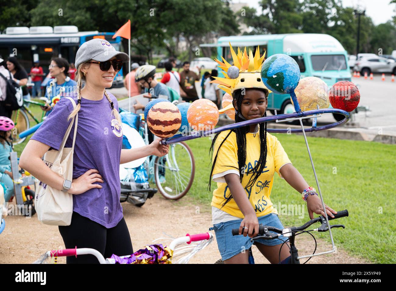 Houston, Stati Uniti. 11 maggio 2024. Una ragazza (R) in sella a una bici artistica a tema solare viene vista al 3rd Art Bike Parade & Festival di Houston, Texas, Stati Uniti, 11 maggio 2024. L'evento annuale ha attirato centinaia di persone per mostrare la loro creatività nella progettazione di biciclette e divertirsi in varie attività. Crediti: Chen Chen/Xinhua/Alamy Live News Foto Stock