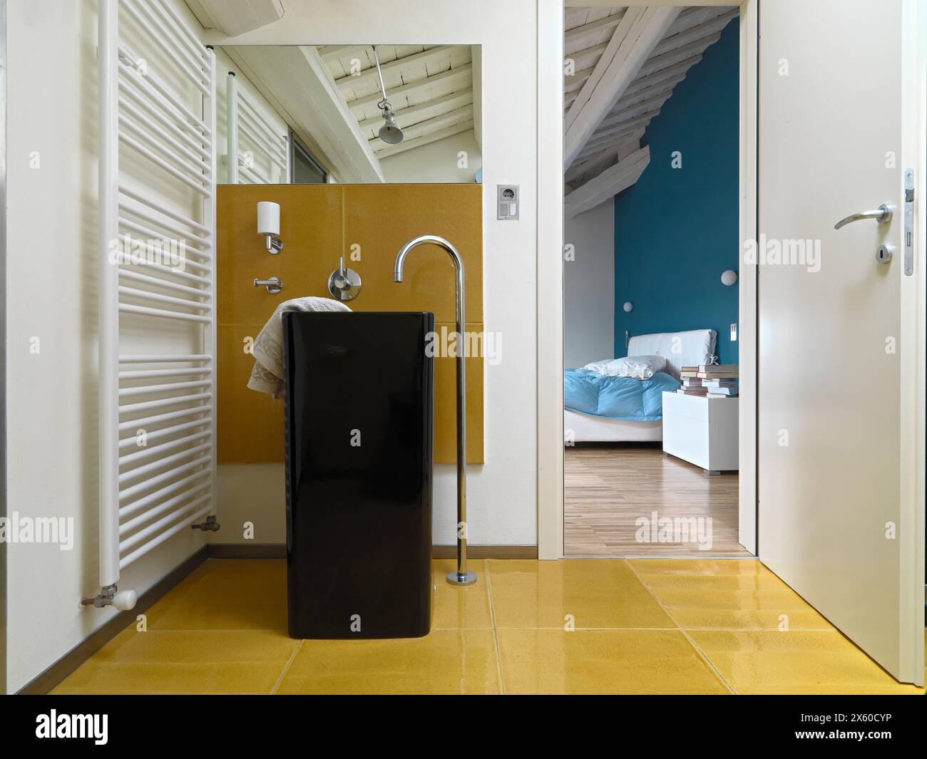 Immagine interna di un bagno moderno nell'appartamento attico, con un lavandino a piedistallo in primo piano e vista sulla camera da letto sulla destra Foto Stock