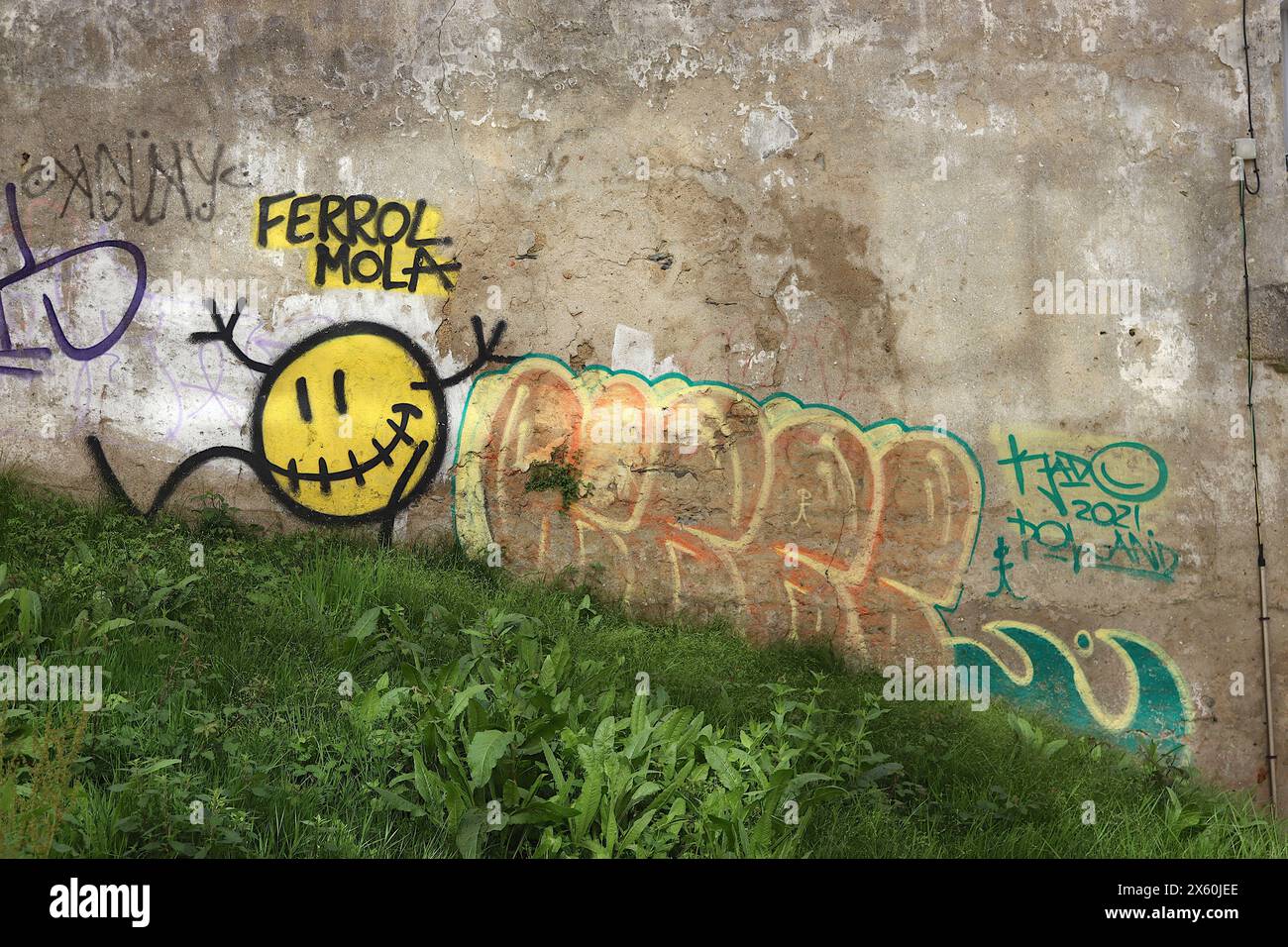 Arte di strada molare di Ferrol, spruzzata su un muro arruffato di un vecchio edificio con una banca erbosa nelle strette stradine secondarie di Ferrol, nel nord della Spagna 2024. Foto Stock