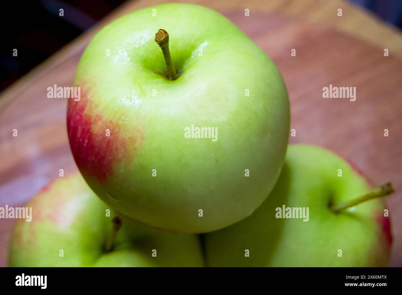 Display Apple organico. Mele verdi, una in primo piano, su uno sfondo rustico in legno. Foto Stock