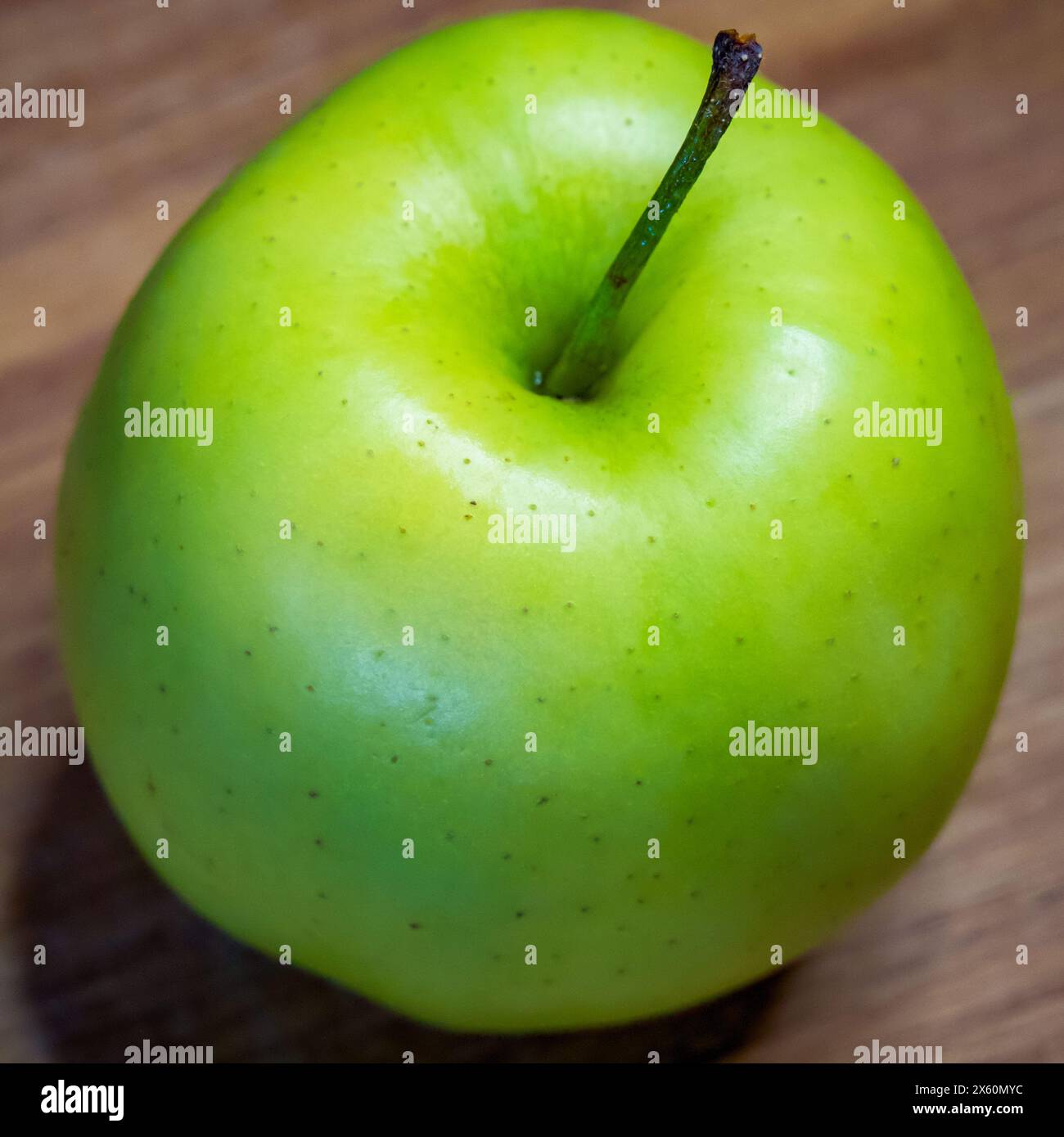 La superficie in legno sotto la mela aggiunge una sensazione rustica e organica. Foto Stock