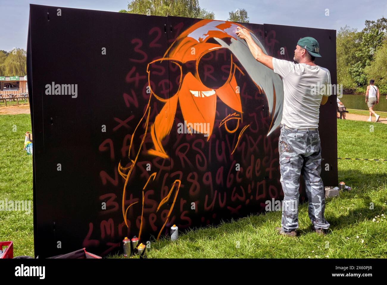 Artista che utilizza una bomboletta spray spray per creare opere d'arte su una tavola Foto Stock