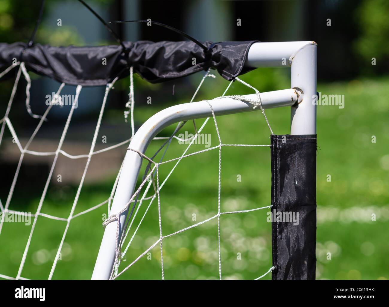 Primo piano di un obiettivo di calcio fai da te realizzato con tubi in PVC bianco con rete usurata in un parco, perfetto per temi ricreativi o sportivi della comunità. Foto Stock