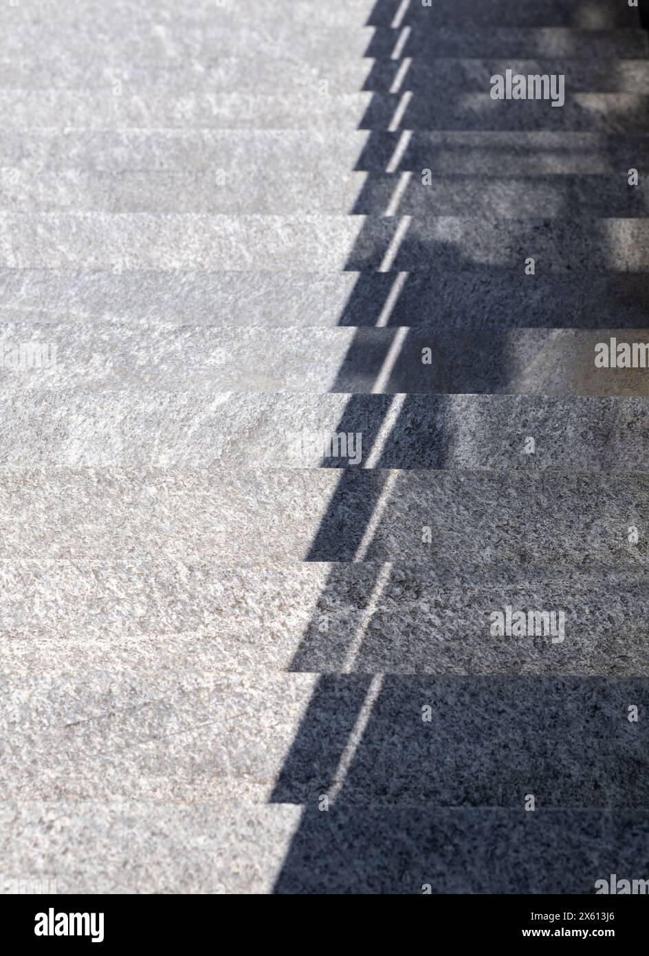 Cattura il gioco di luci e ombre su scale in pietra all'aperto, creando un sorprendente motivo geometrico sotto la luce del sole. Foto Stock