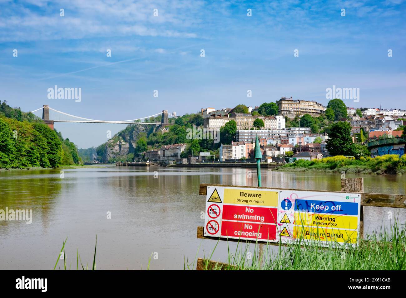 Vista dall'alta marea lungo il fiume Avon, Bristol, Regno Unito, verso il ponte sospeso di Clifton. Un segnale avverte di pericolose correnti fluviali e di non nuotare Foto Stock