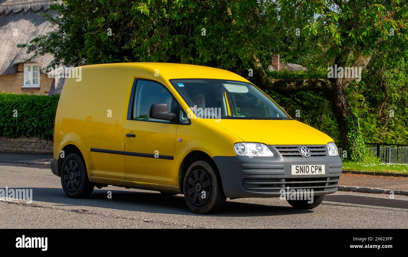 Stoke Goldington, Regno Unito - 12 maggio 2024:2010 un furgone Volkswagen Caddy giallo che attraversa un villaggio inglese Foto Stock