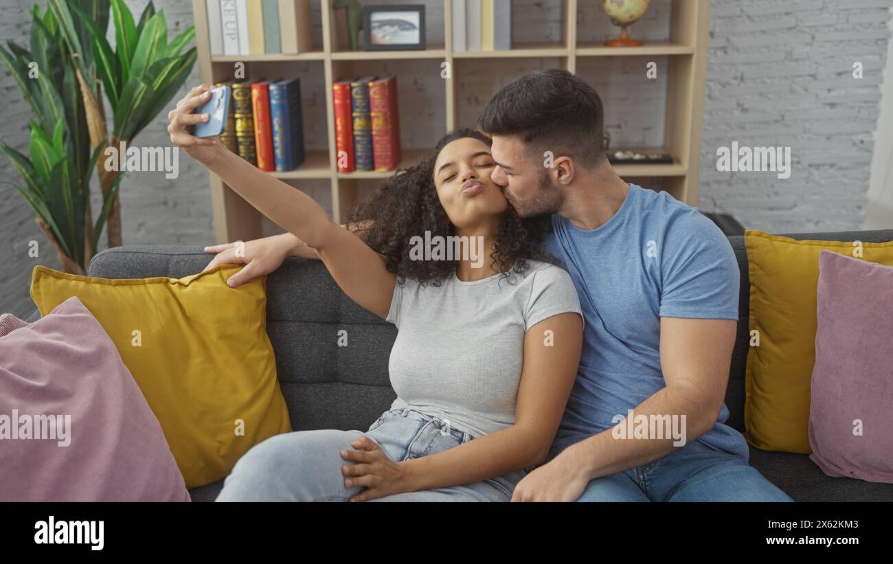 La coppia scatta un selfie in un accogliente soggiorno, mostrando amore e solidarietà in un ambiente familiare informale. Foto Stock