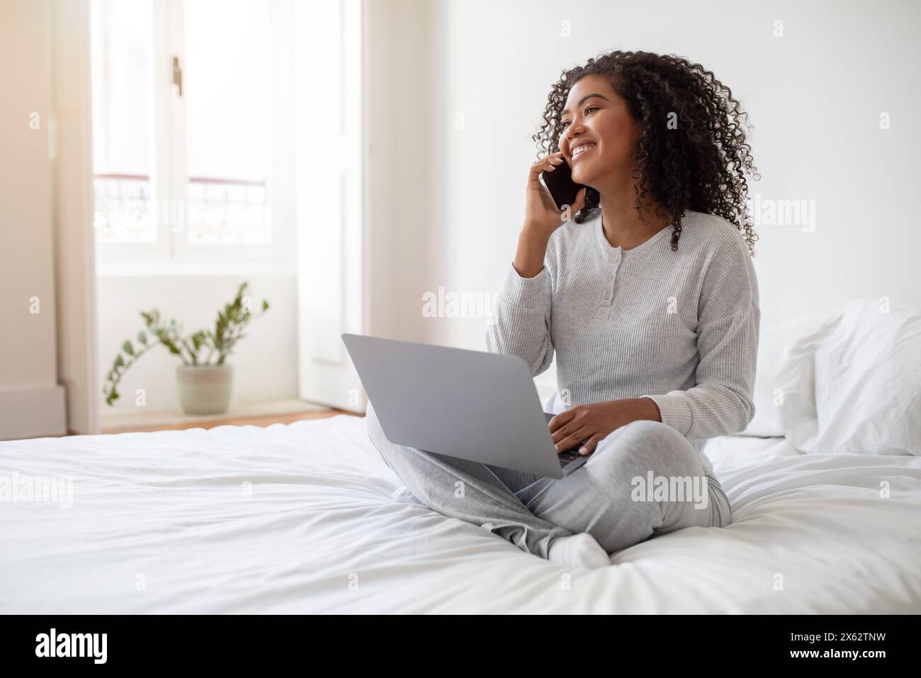 Sorridente giovane donna che lavora da casa sul suo notebook Foto Stock