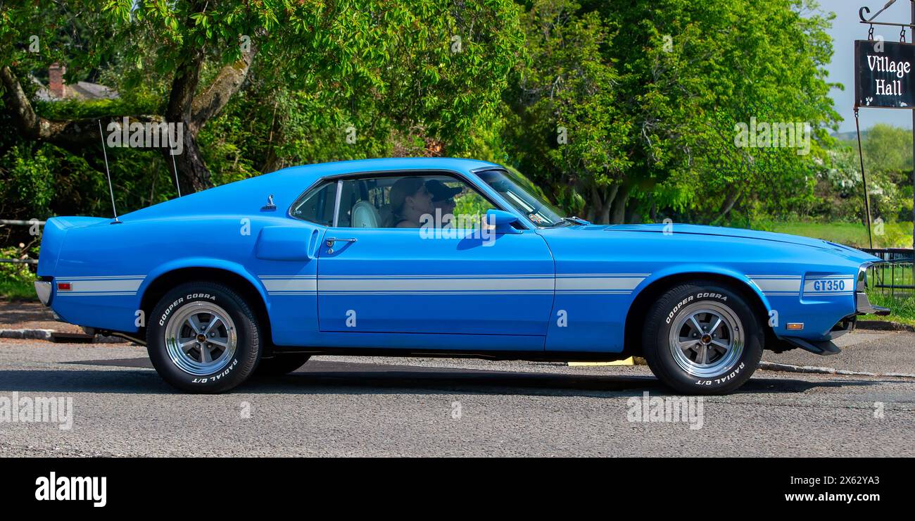 Stoke Goldington, Regno Unito - 12 maggio 2024:1969 Ford Shelby, auto d'epoca blu che guida su una strada inglese Foto Stock
