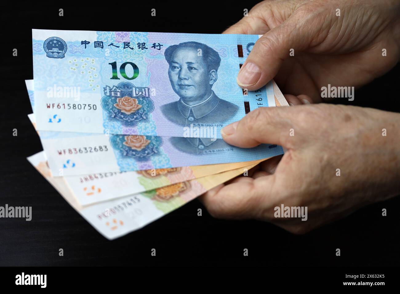 Donna anziana con banconote yuan in mani ruggite. Concetto di pagamenti pensionistici in Cina, risparmio al pensionamento, pensionato cinese con denaro Foto Stock