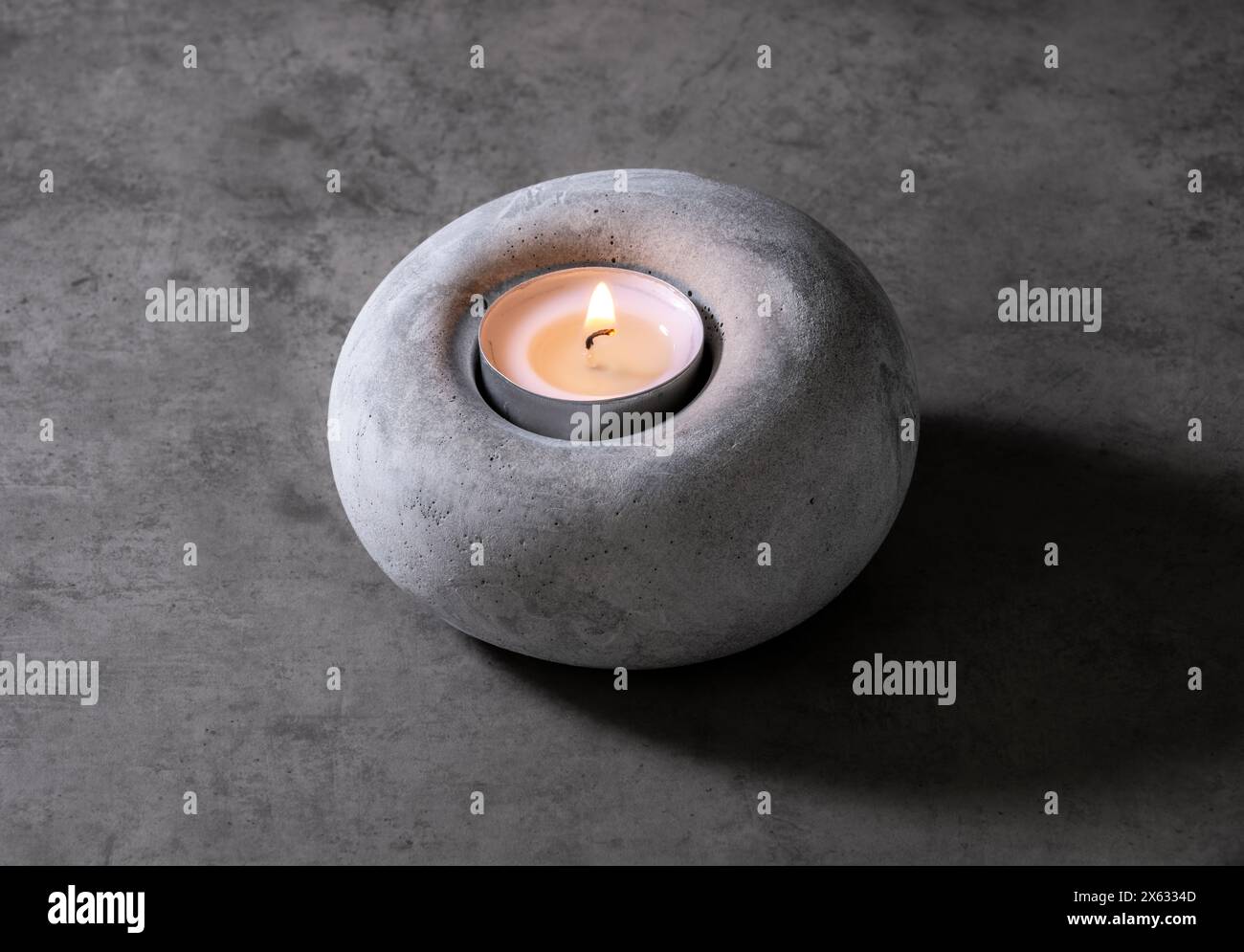 Bruciatura Tealight in un portacandele in cemento Foto Stock