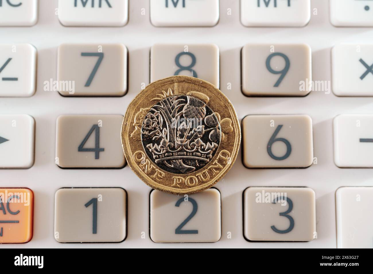Moneta inglese da una sterlina posta sopra i pulsanti della calcolatrice. Concetto di business, pianificazione e finanza Foto Stock
