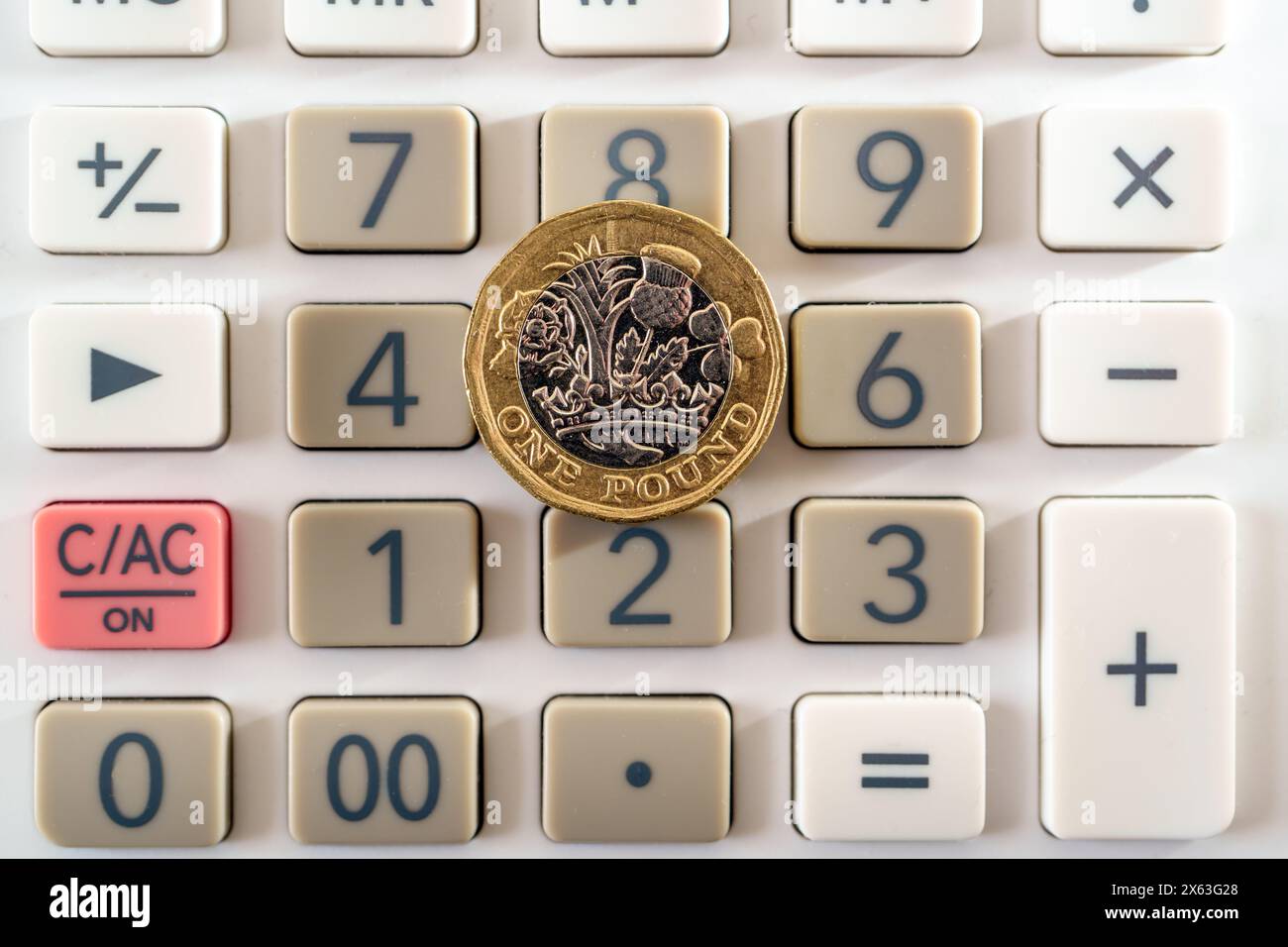 Moneta inglese da una sterlina posta sopra i pulsanti della calcolatrice. Concetto di business e finanza. Foto Stock