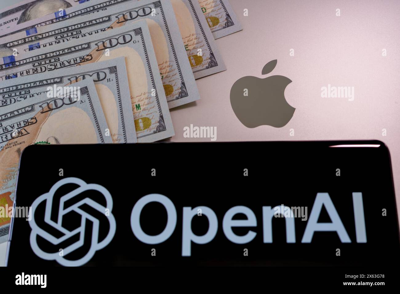 Notebook Apple parzialmente coperto da bollette da cento dollari USA - concetto di tecnologia e finanza. Stafford, Regno Unito, 28 aprile 2024 Foto Stock