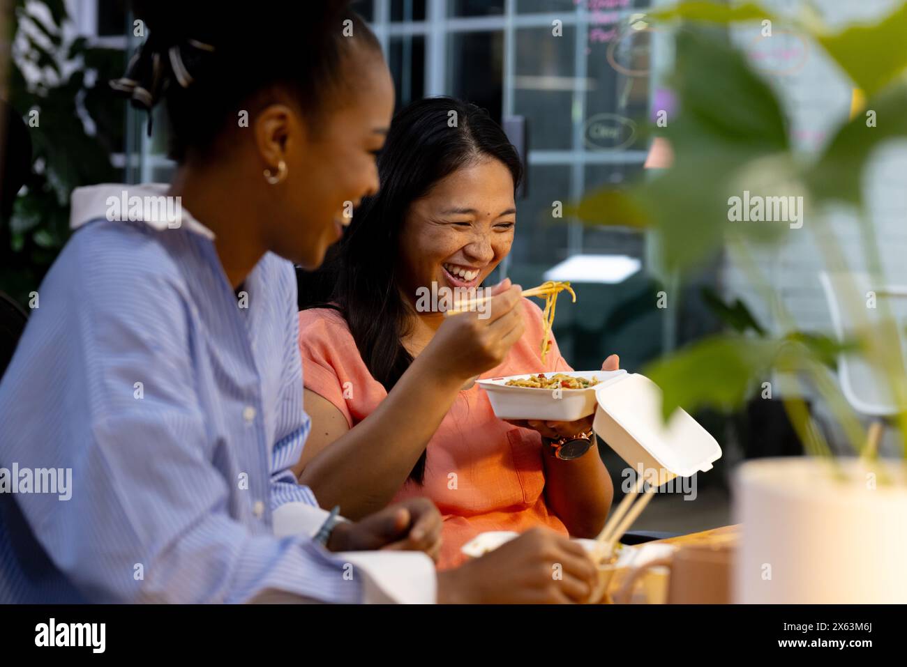 In ufficio, diverse colleghe d'affari si divertono a mangiare insieme, lavorando fino a tardi Foto Stock