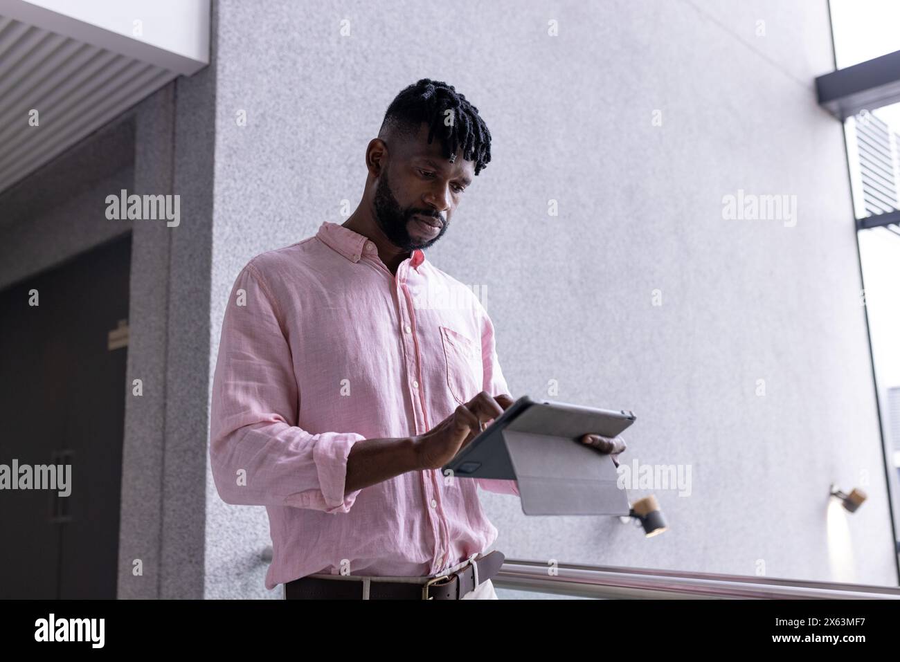 Un uomo afroamericano di mezza età legge da un tablet in ufficio Foto Stock