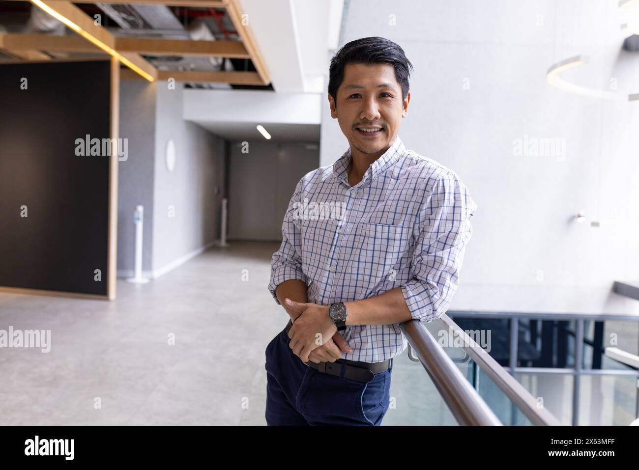 Uomo asiatico professionista in piedi da solo in ufficio, appoggiato su ringhiere Foto Stock