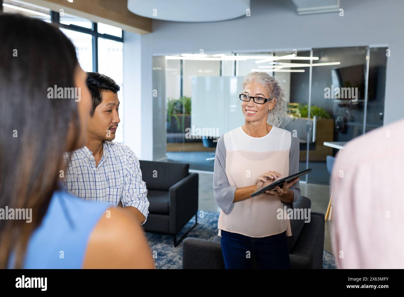 Team diversificato in ufficio che ascolta mentre una donna professionista spiega Foto Stock