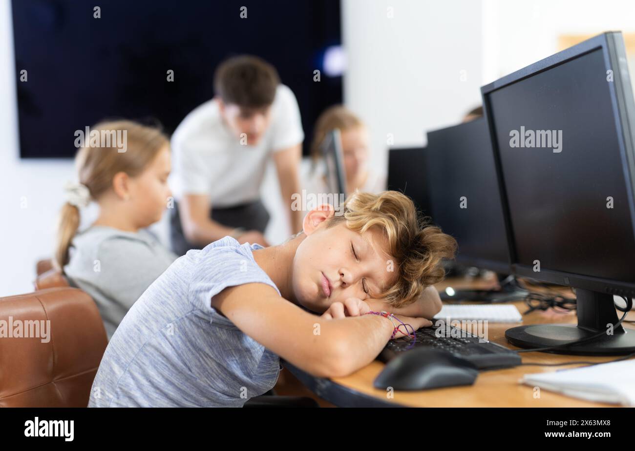 Stanca studentessa maschio si addormentò con la tastiera del computer in classe Foto Stock